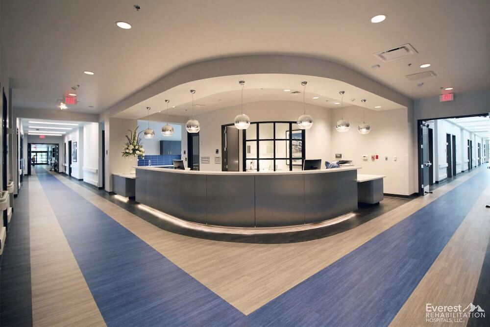 A modern office featuring a curved reception desk and luxury vinyl tile flooring designed for sound absorption