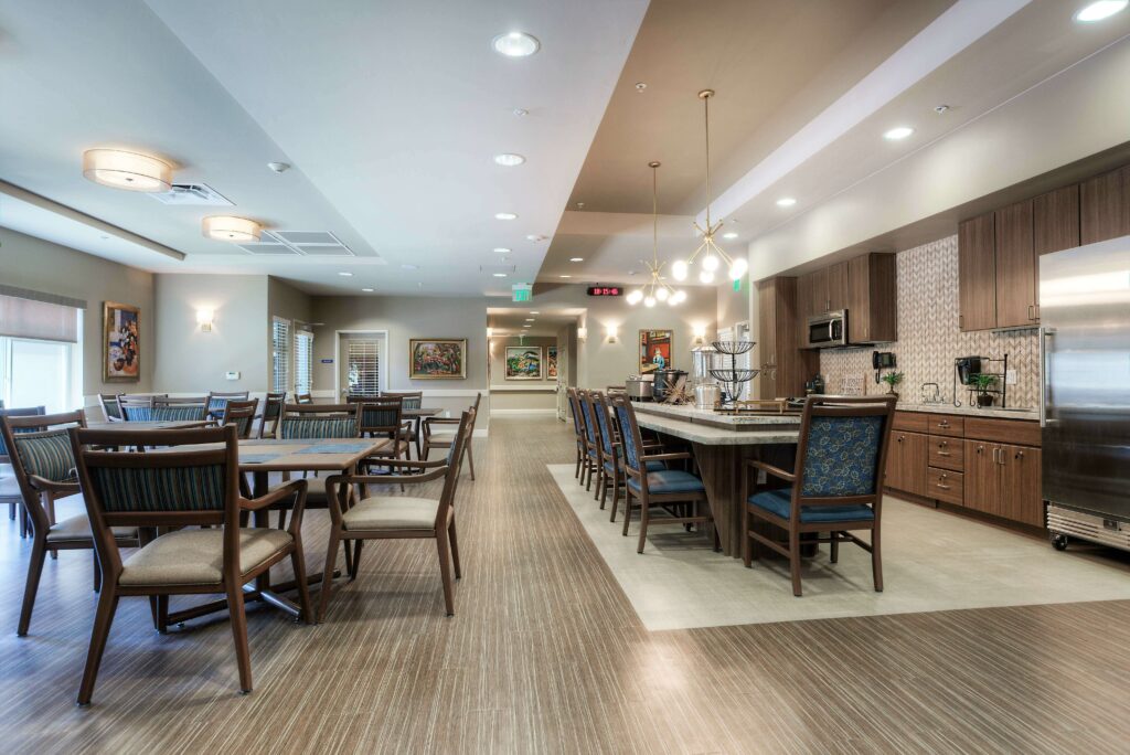 Rosewood LVT flooring in a corporate dining area with wooden chairs and tables, adjacent to a kitchen with a marble countertop and wooden cabinetry.