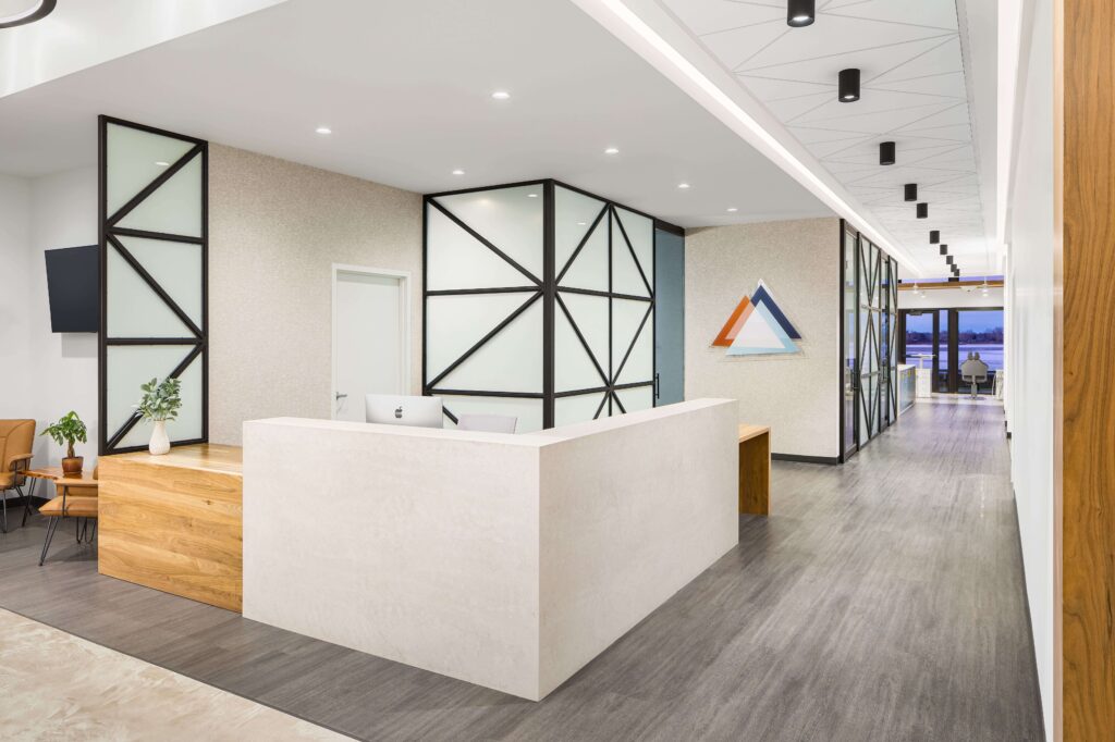 A modern healthcare reception area with mixed wood furnishings and luxury vinyl tile flooring.