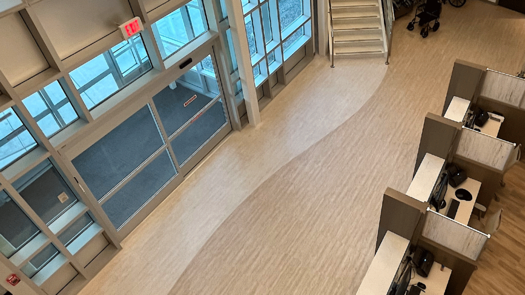 Curved luxury vinyl tile flooring in a large open healthcare facility, exemplifying modern healthcare design with a seamless blend of neutral tones.