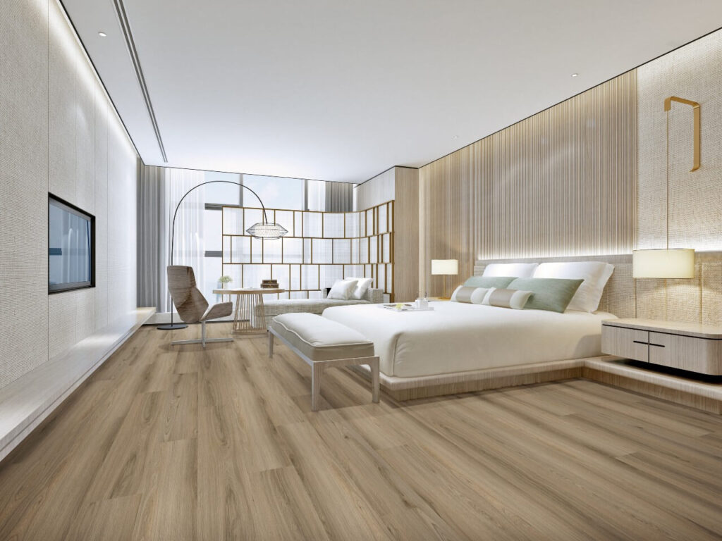 A modern hotel bedroom with wood-look Rigid Core Click flooring, a platform bed with white bedding, a cushioned bench, and soft ambient lighting.