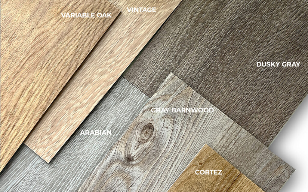 Luxury vinyl plank wood samples from the TAJ Select Woods collection, showcasing the colors Variable Oak, Vintage, Dusky Gray, Arabian, Gray Barnwood, and Cortez, highlighting a range of warm, cool, and weathered wood visuals for commercial flooring.